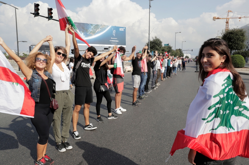 Lebanese protesters hold hands to form a human chain along the coast from north to south as a symbol of unity, during ongoing anti-government demonstrations in Lebanon's capital Beirut on October 27, 2019. / AFP / ANWAR AMRO