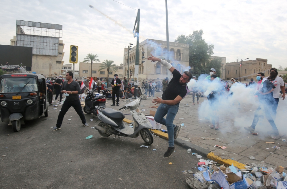 An Iraqi protester throws back a tear gas canister amid clashes with security forces during an anti-government demonstration in Iraq's capital Baghdad on October 27, 2019.   AFP 