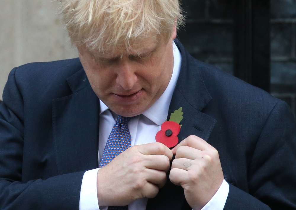 Britain's Prime Minister Boris Johnson pins a poppy to his lapel on the steps of 10 Downing street as he meets with fundraisers for the Royal British Legion in central London on October 28, 2019. AFP / ISABEL INFANTES