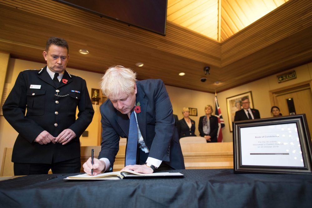 Britain's Prime Minister Boris Johnson signs a book of condolence during a visit to Thurrock Council Offices in Thurrock, east of London on October 28, 2019, following the October 23, 2019, discovery of 39 bodies concealed in a lorry.  AFP / Stefan Rousse