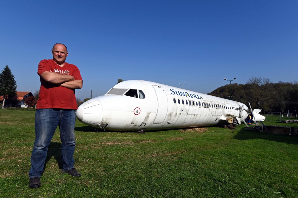 Croatian citizen Robert Sedlar poses in front of a former SunAdria Holland Fokker-100 aircraft in his garden in Strmec Stubicki, near Zagreb, Croatia, on October 26, 2019. AFP / Denis Lovrovic  