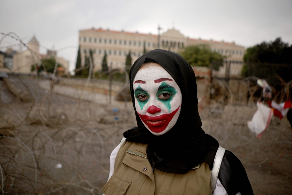 A Lebanese woman with her face painted with the character of the Joker takes part in a protest in downtown Beirut on October 23, 2019.  AFP / Patrick Baz 