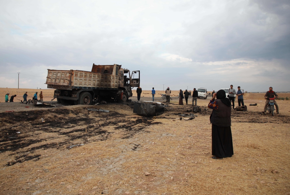 Syrian locals near a destroyed truck at the spot where Abu Hassan al-Muhajir, the Islamic State (IS) group's spokesman was reportedly killed in a raid in the northern Syrian village of Ayn al-Bayda near Jarablus. AFP / Aaref WATAD