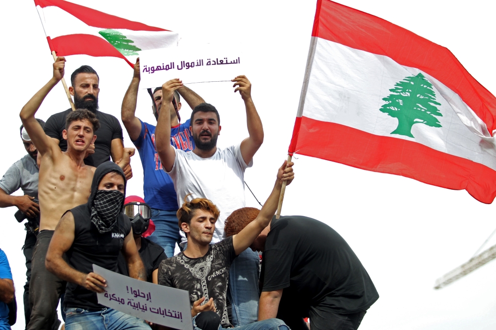 Lebanese demonstrators wave the national flag during a protest against dire economic conditions in downtown Beirut on October 18, 2019. AFP / Ibrahim Amro