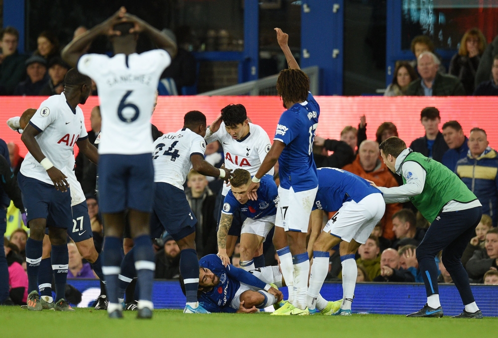 Teammates comfort Everton's Portuguese midfielder André Gomes (C floor) as he gets attention for an injury as Everton's Irish defender Seamus Coleman (R) looks on during the English Premier League football match between Everton and Tottenham Hotspur at Go