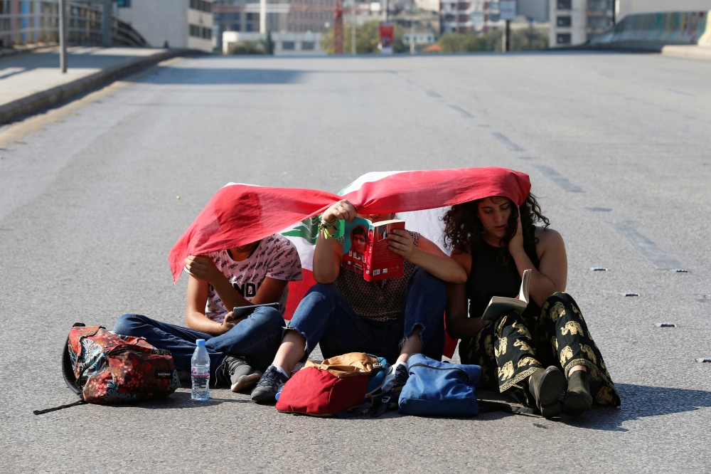 Demonstrators sit on the ground and read along a blocked road during ongoing anti-government protests in Beirut, Lebanon November 4, 2019. REUTERS/Mohamed Azakir