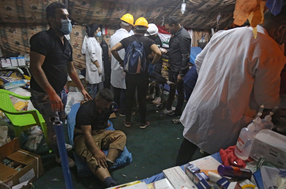 Iraqi paramedics aid injured protesters following clashes with security forces on al-Ahrar bridge in the capital Baghdad during ongoing anti-government demonstrations on November 4, 2019.  AFP / AHMAD AL-RUBAYE