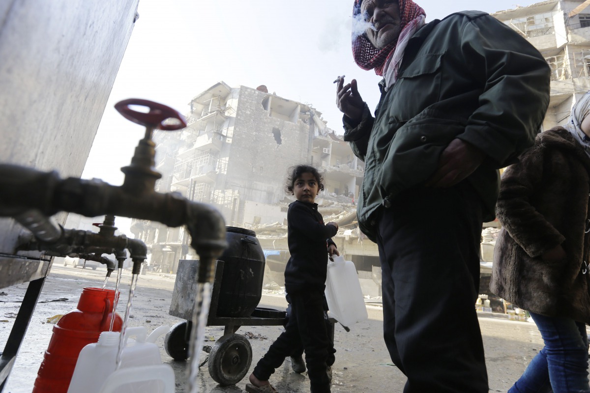 Syrians standing next to water faucets as they fill jerrycans in al-Shaar neighbourhood, Aleppo on January 21, 2017. AFP / Louai Beshara