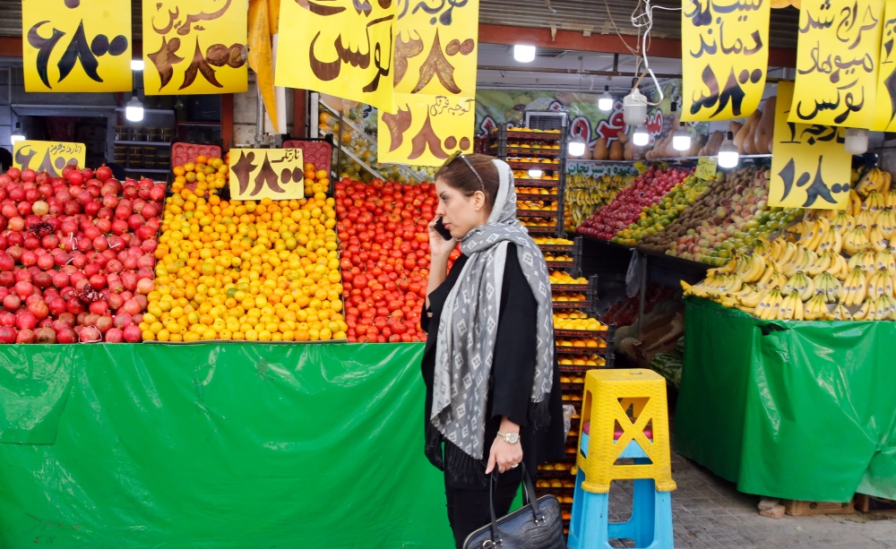 An Iranian woman speaks on her mobile phone as she walks past a fruit shop in central Tehran on November 7, 2019. AFP 