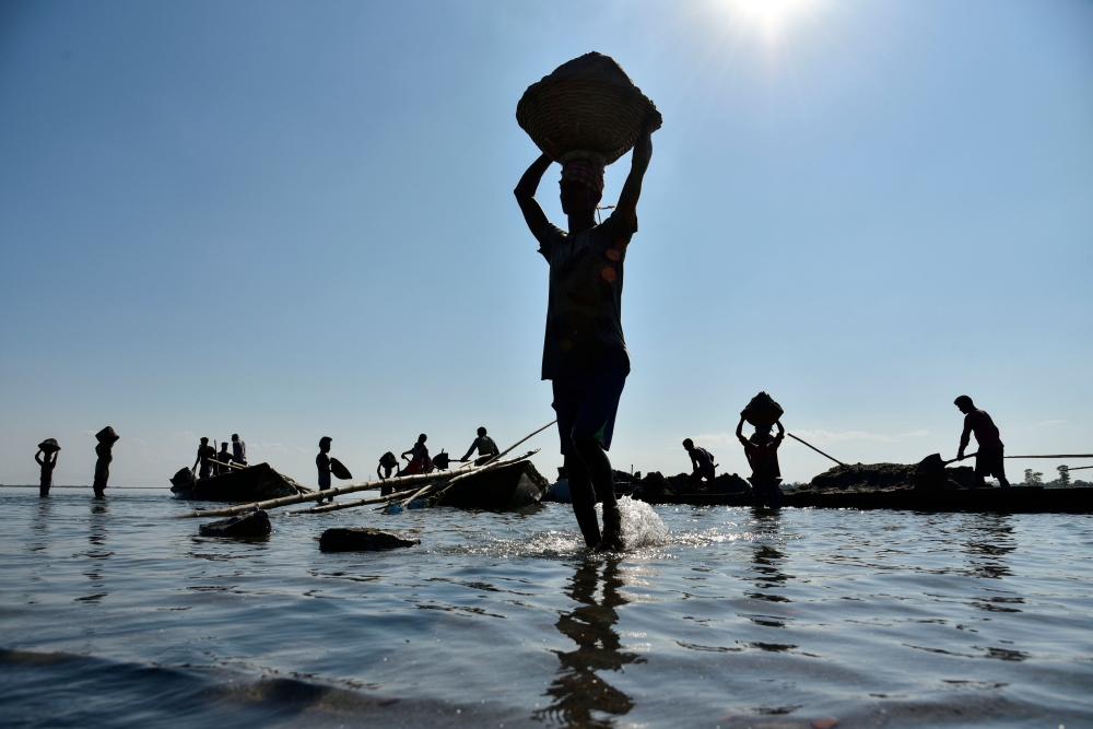 Labourers extract sand from the riverbed of the Beki River in the district of Barpeta of the northern Indian state of Assam on November 4, 2019. AFP / David Talukdar
 