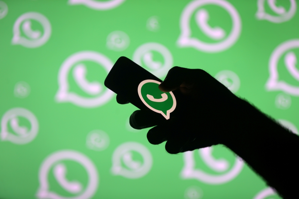 A man poses with a smartphone in front of displayed Whatsapp logo in this illustration, September 14, 2017. Reuters / Dado Ruvic