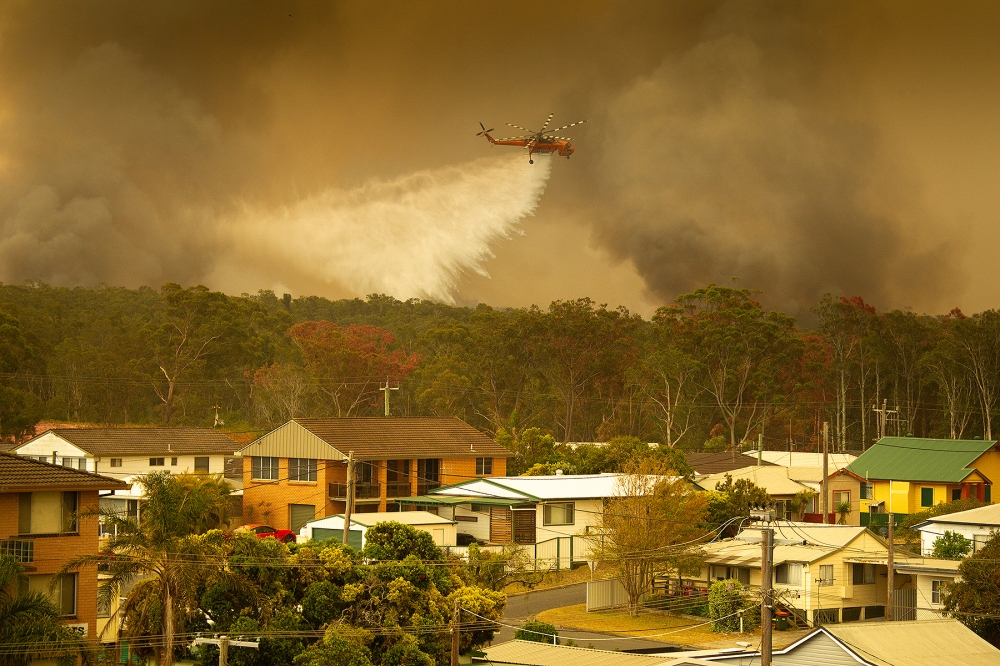 An Air-crane water bombing helicopter drops water on a bushfire in Harrington, Australia, November 8, 2019. AAP Image/Shane Chalker/via Reuters 