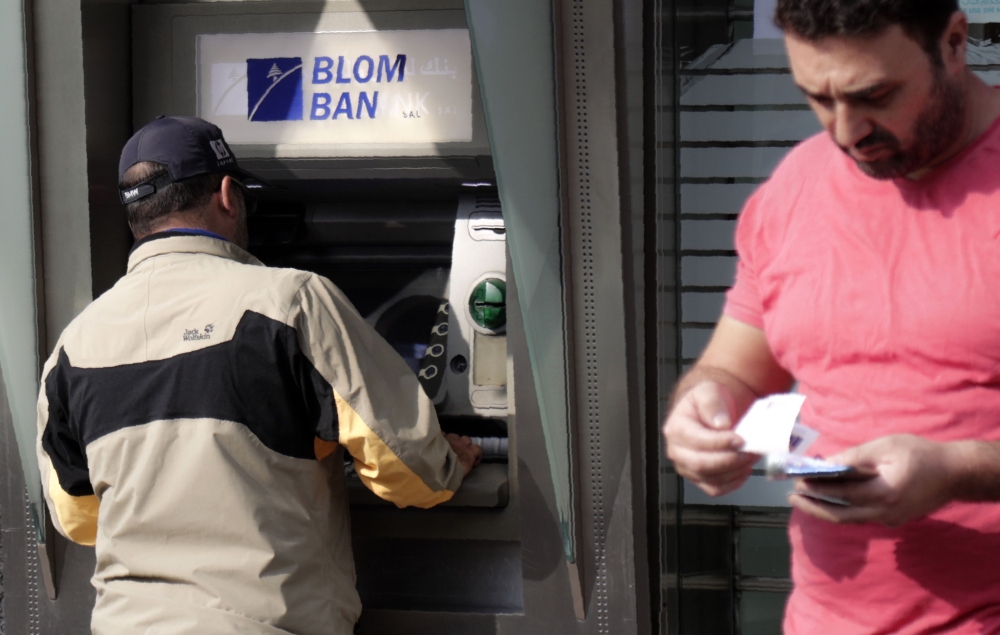 A man withdraws cqsh from an ATM machine in the Lebanese capital Beirut on November 9, 2019.  AFP / ANWAR AMRO