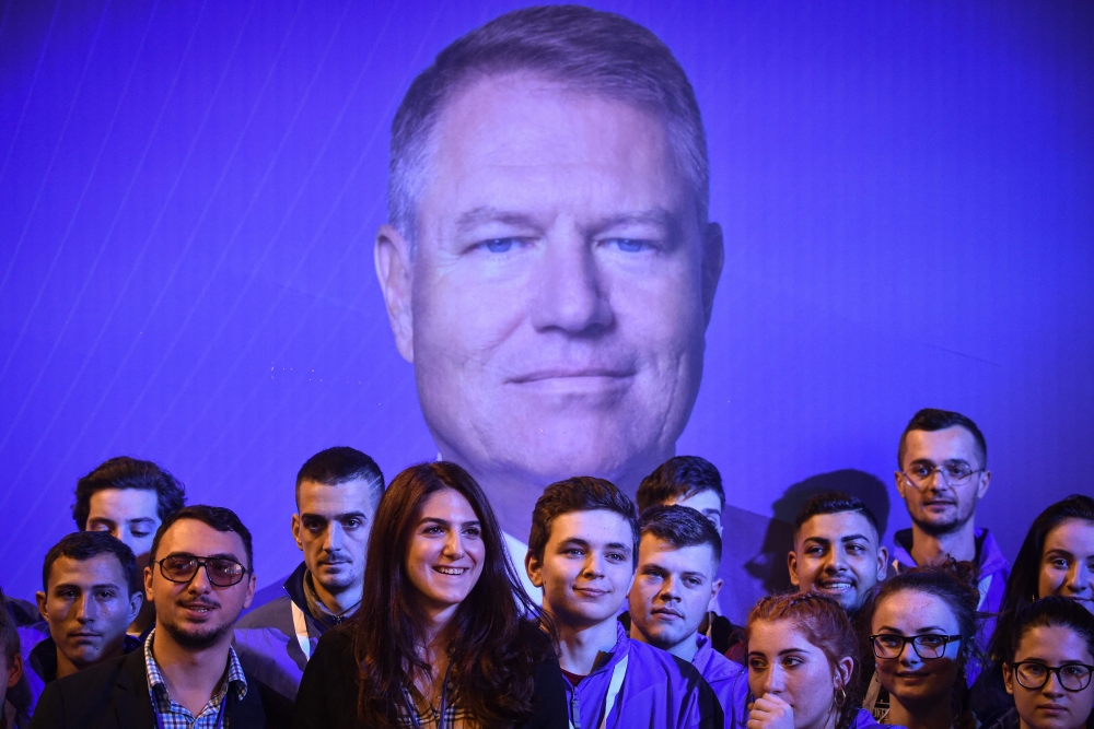 File photo of supporters of Romanian President Klaus Iohannis stand in front of his picture at an electoral meeting at the sports hall in Braila city (south-east Romania) November 6, 2019. / AFP / Daniel MIHAILESCU 
