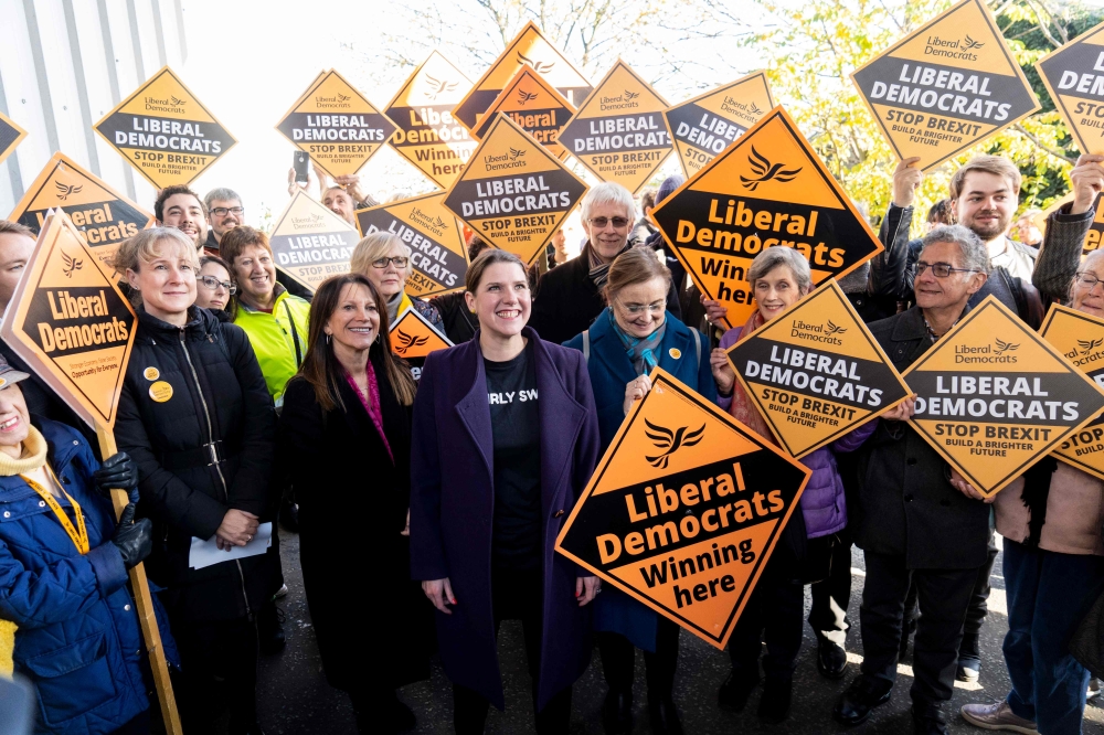 Britian's Liberal Democrats leader Jo Swinson (C) poses with supporters as she leaves Total Boxer, a boxing gym offering training to young people as a means of keeping them away from violence, campaigning for the general election in northeast London on No
