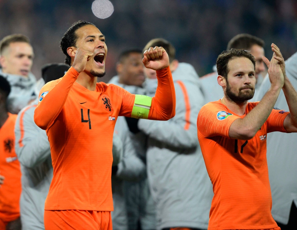 Netherlands' defender Virgil van Dijk (L) and Netherlands' defender Daley Blind (R) celebrate their qualification for the finals on the pitch after the Euro 2020 qualification football match between Northern Ireland and Netherlands at Windsor Park in Belf