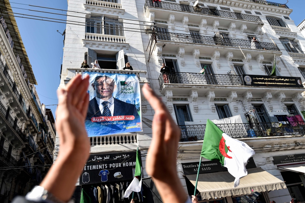 A supporters of Abdelkader Bengrina, former Algerian tourism minister and presidential candidate for the El-Bina (Construction) Islamist party, applauds outside his electoral campaign headquarters in the capital Algiers on November 17, 2019. AFP / Ryad Kr