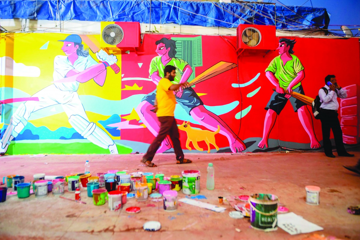 A man walks past cricket themed mural paintings on the walls of Eden Gardens ahead of the first pink ball day-night Test cricket match between India and Bangladesh, in Kolkata on November 18, 2019. AFP / Dibyangshu Sarkar
