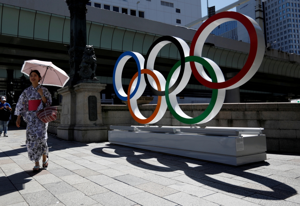 File photo of a woman wearing the yukata, or casual summer kimono, walks past Olympic rings displayed at Nihonbashi district in Tokyo, Japan August 5, 2019. REUTERS/Issei Kato/File Photo
 