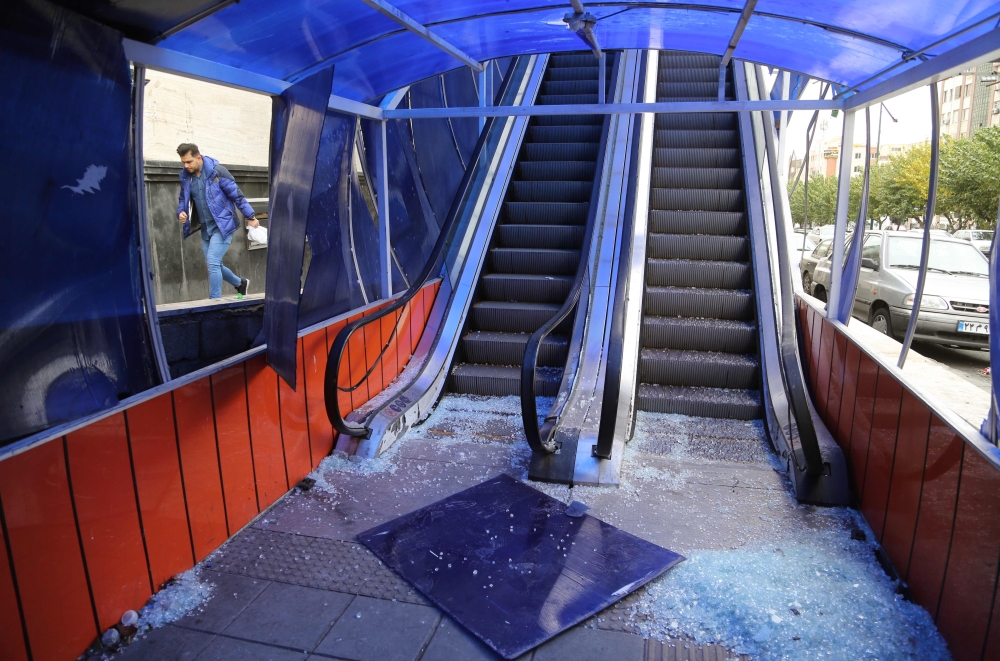 An Iranian man walks past the entrance of a pedestrian overpass that was vandalised by protesters in Tehran on November 19, 2019. AFP / Atta Kenare