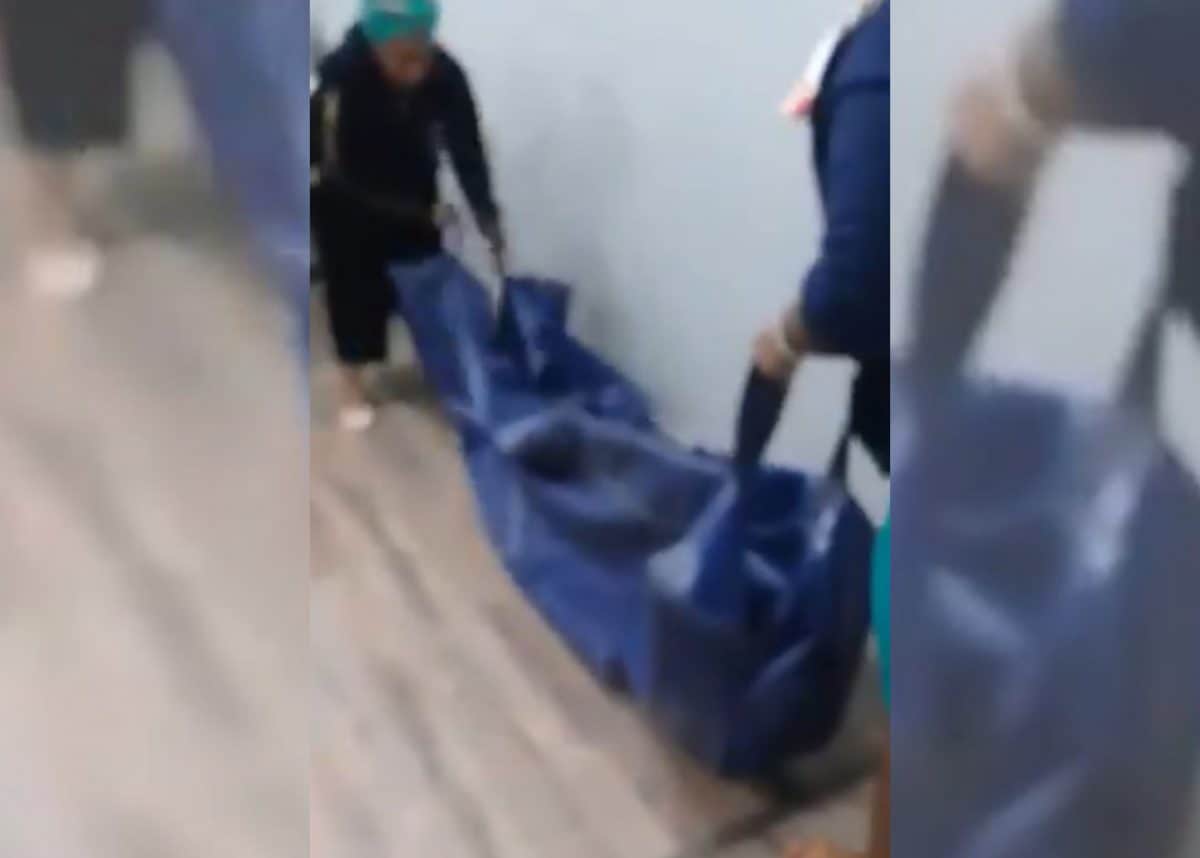 In a video clip that has gone viral on social media, two women can be seen schlepping a blue plastic body bag into an insurance office as stunned clients look on.