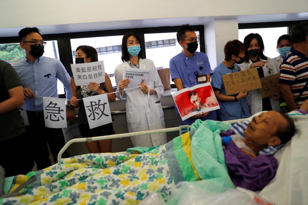 A patient is wheeled past as healthcare staff hold posters and participate in a human chain to protest against what they say is police brutality during the anti-extradition bill protests, at Queen Mary Hospital, in Hong Kong, September 2, 2019. Reuters/An