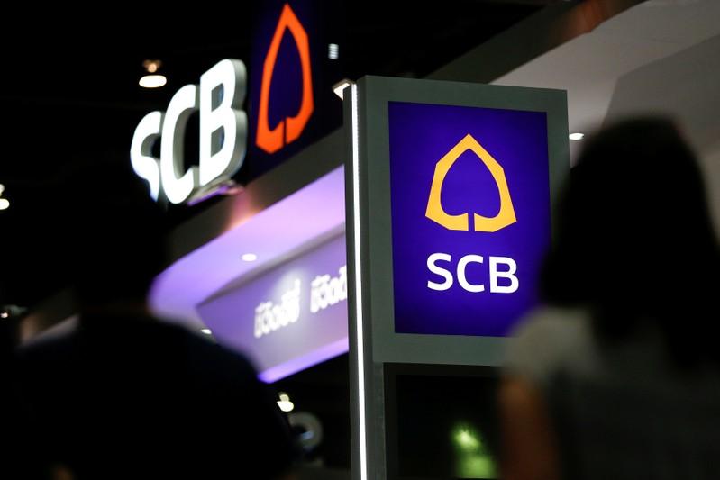 People walk pass the logos of Siam Commercial Bank at an exhibition hall in Bangkok, Thailand, May 12, 2016. Reuters/Athit Perawongmetha