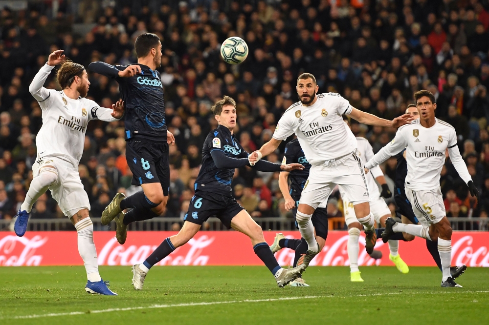 Real Madrid's French forward Karim Benzema (2R) prepares to shoot and score a goal during the Spanish league football match Real Madrid CF against Real Sociedad at the Santiago Bernabeu stadium in Madrid on November 23, 2019. / AFP / PIERRE-PHILIPPE MARCO