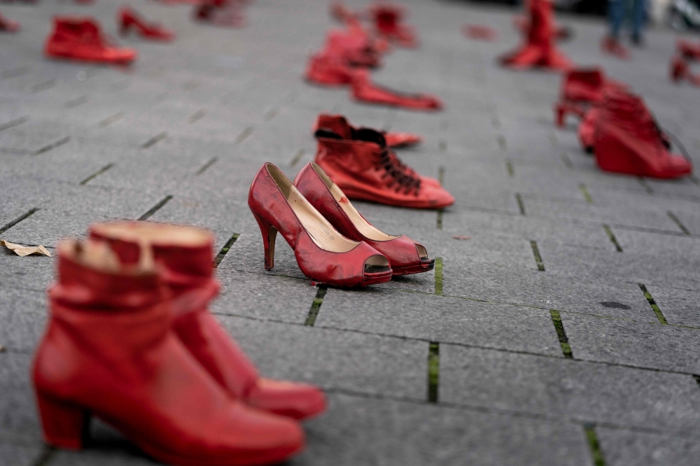 A picture taken on November 24, 2019, in Brussels shows red shoes set up on the ground for the victims during a protest to condemn violence against women. AFP / Kenzo Tribouillard
 