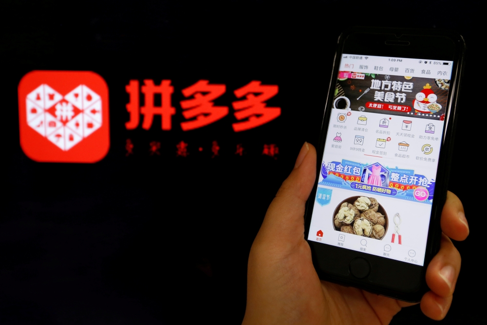 FILE PHOTO: The logo of Chinese online group discounter Pinduoduo is seen next to its mobile phone app in this illustration picture taken July 17, 2018. REUTERS/Florence Lo/File Photo