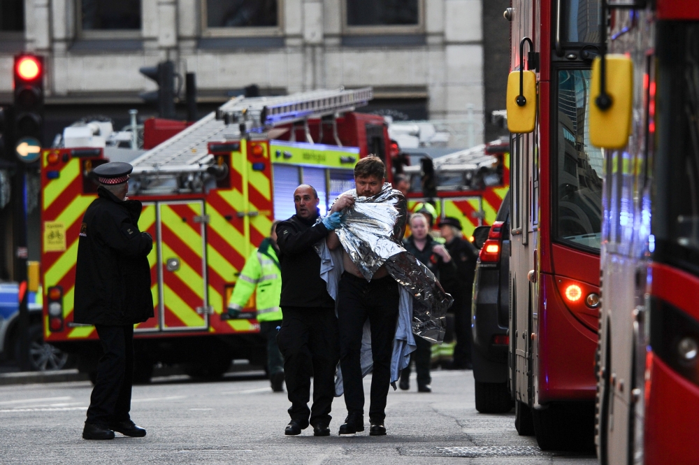 Police assist an injured man near London Bridge in London, on November 29, 2019 after reports of shots being fired on London Bridge. AFP / DANIEL SORABJI