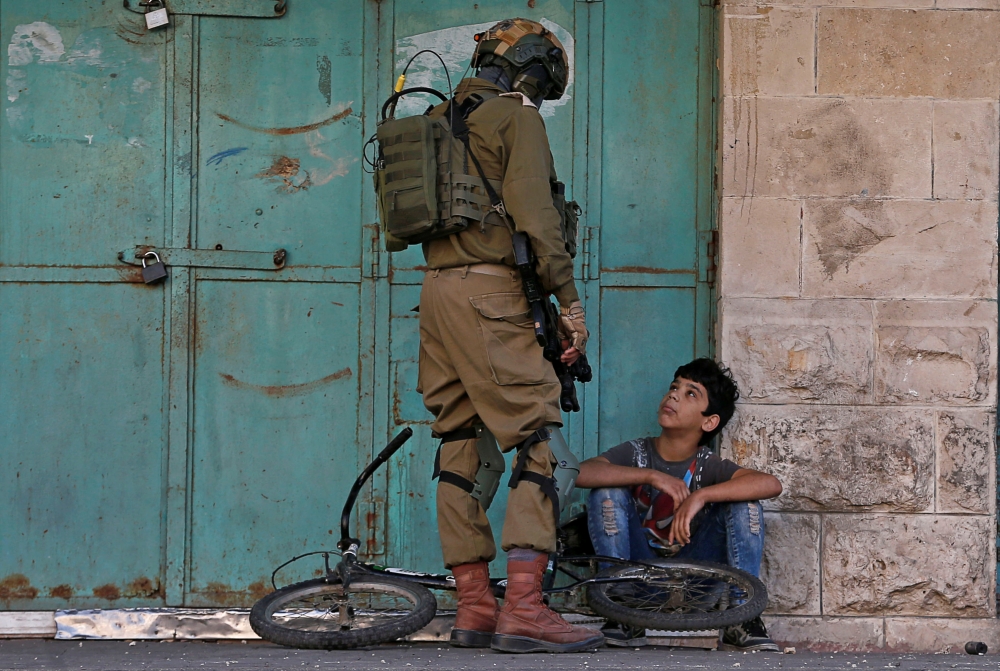 An Israeli soldier detains a Palestinian boy during an anti-Israel protest in Hebron in the Israeli-occupied West Bank November 29, 2019. Reuters/Mussa Qawasma
 
 