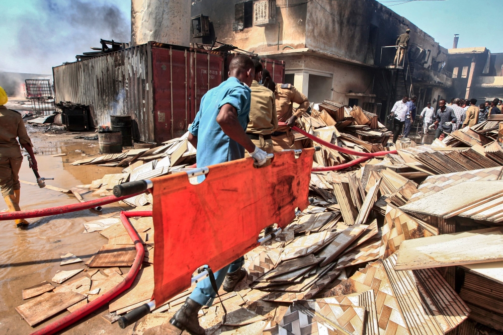 A Sudanese paramedic walks with a stretcher as others search for victims at the scene of a fire at a tile manufacturing unit in an industrial zone in north Khartoum, on December 3, 2019. AFP / Ebrahim Hamid 