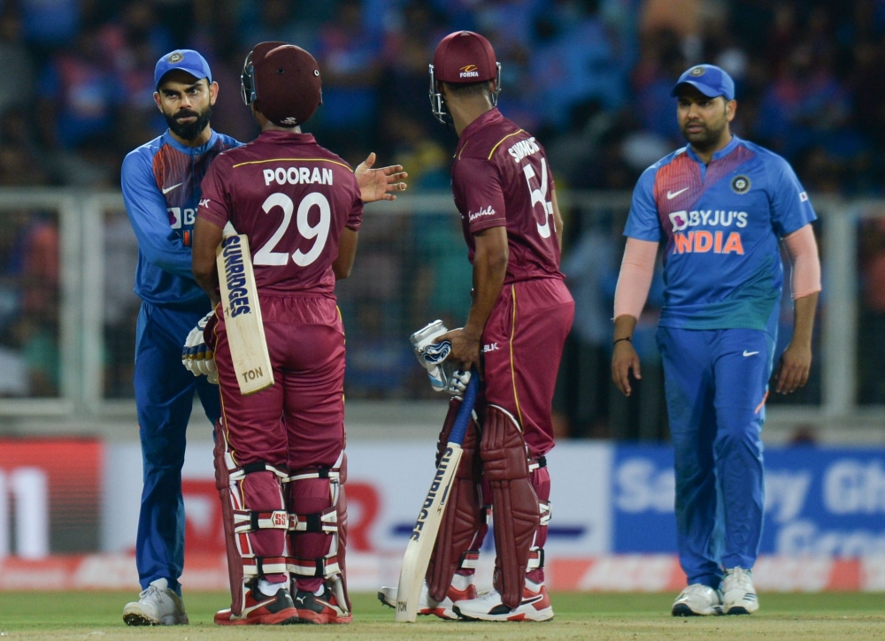 West Indies cricketer Lendl Simmons (R) and Nicholas Pooran (C) speak with Indian cricket captain Virat Kohli (L) after winning the second T20 international cricket match of a three-match series between India and West Indies at the Greenfield Internationa