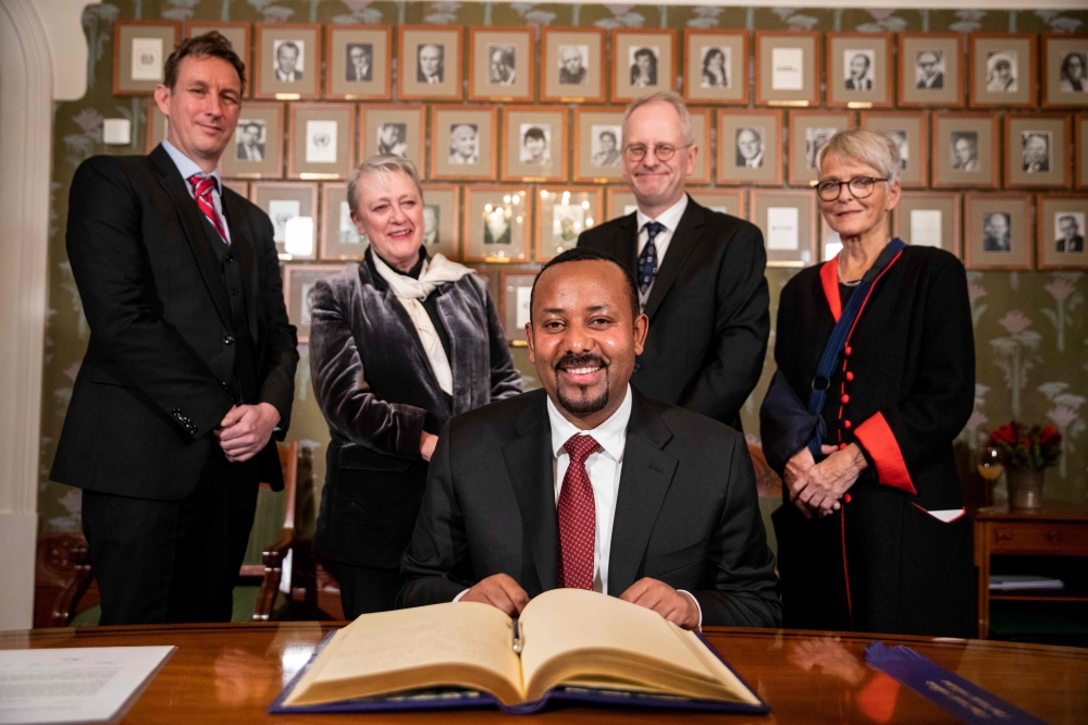 Ethiopia's Prime Minister and this year's Nobel Peace Prize Laureate Abiy Ahmed Ali (C) signs the Nobel Protocol at his arrival in Oslo, Norway, on December 9, 2019; behind (From L) members of the Norwegian Nobel Peace Prize comitee Asle Toje, chairwoman 
