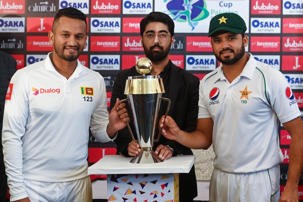 Pakistan's captain Azhar Ali (R) and his Sri Lankan counterpart Dimuth Karunaratne (L) pose for a photograph with Test series trophy at the Pindi Cricket Stadium ahead of the first Test cricket match between Pakistan and Sri Lanka in Rawalpindi on Decembe