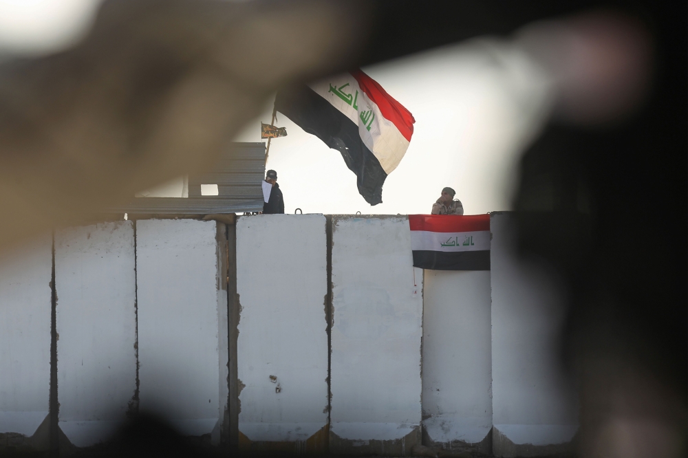  Iraqi security forces observe protesters from their checkpoint at al-Sinek bridge in the capital Baghdad amid ongoing anti-government demonstrations on December 12, 2019. / AFP / AHMAD AL-RUBAYE