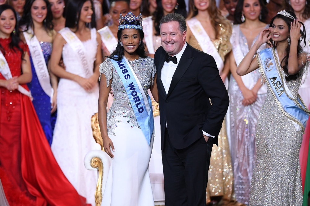 Newly crowned Miss World 2019 Miss Jamaica Toni-Ann Singh smiles as she poses with TV presenter Piers Morgan (R) during the Miss World Final 2019 at the Excel arena in east London on December 14, 2019. / AFP / DANIEL LEAL-OLIVAS
