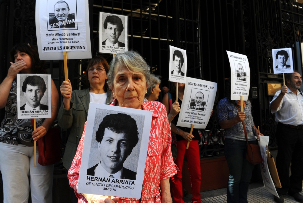 In this file photo taken on April 09, 2014 Beatriz Cantarini de Abriata, mother of Hernan Abriata, arrested in 1976 in Argentina and missing, holds a portrait of her son next to relatives and friends holding also the portrait of former Argentine police of