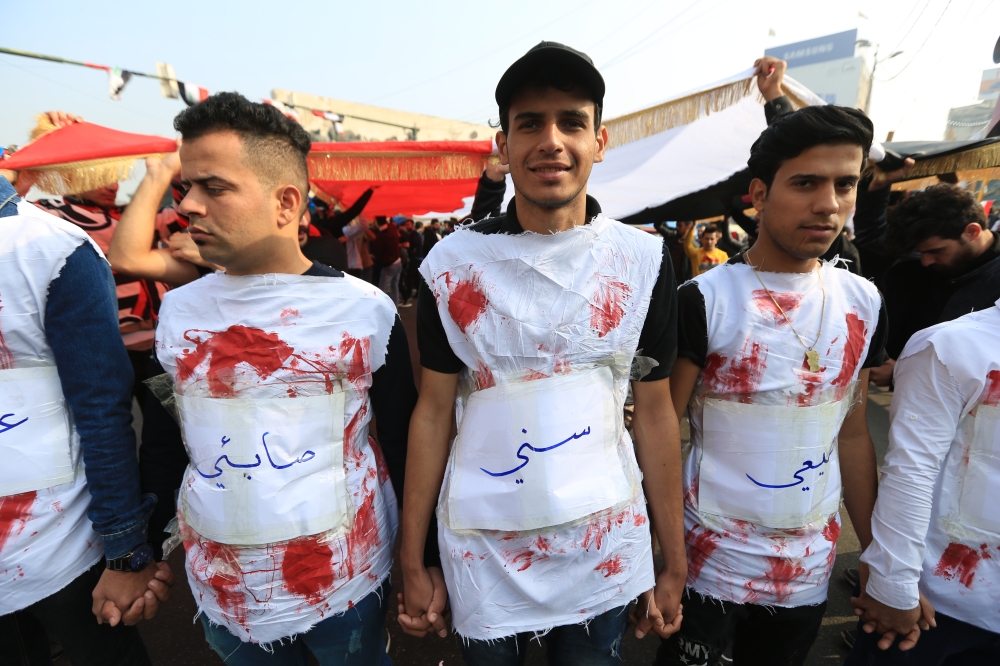 Protesters stage a protest with symbolic blooded clothes to draw attention to the human rights violations suffered by Iraqi people as they continue their anti-government demonstrations in Baghdad, Iraq on December 15, 2019. (Murtadha Sudani/Anadolu Agency