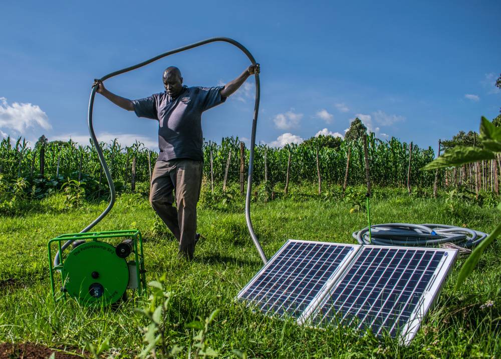 A Kenyan farmer carries the hose of his solar water pump in Kisumu county, Kenya on June 2018. Photo Courtesy: Futurepump/Dan Odero
