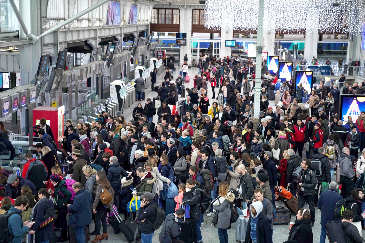 Travelers wait to board their train as Gare de Lyon railway station in Paris on December 20, 2019, on the 16th day of a nationwide multi-sector strike against the government's pensions overhaul. / AFP / Martin Bureau

