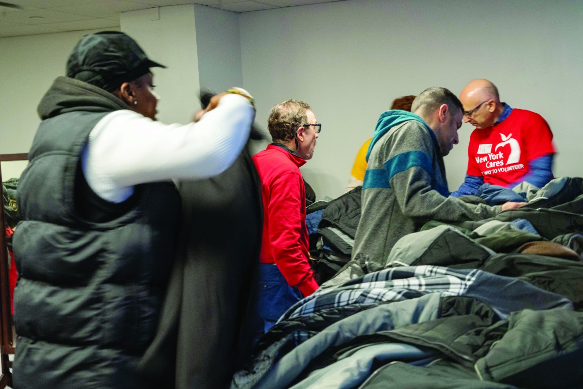 People in need of coats pick from a table of jackets on December 24, 2019 in New York City. New York Cares has collected 50,000 of the 100,000 coats it aims to collect and distribute to its hundreds of school and nonprofit partners in the 31st annual coat
