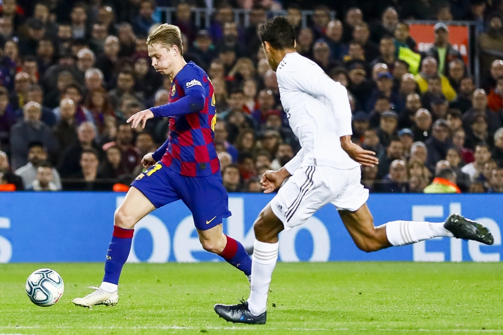 Barcelona's Dutch midfielder Frekie De Jong (L) vies with Real Madrid's French defender Raphael Varane (R) during Spanish El Clasico football match between FC Barcelona and Real Madrid at the Camp Nou stadium in Barcelona on December 18, 2019. Adria Puig 