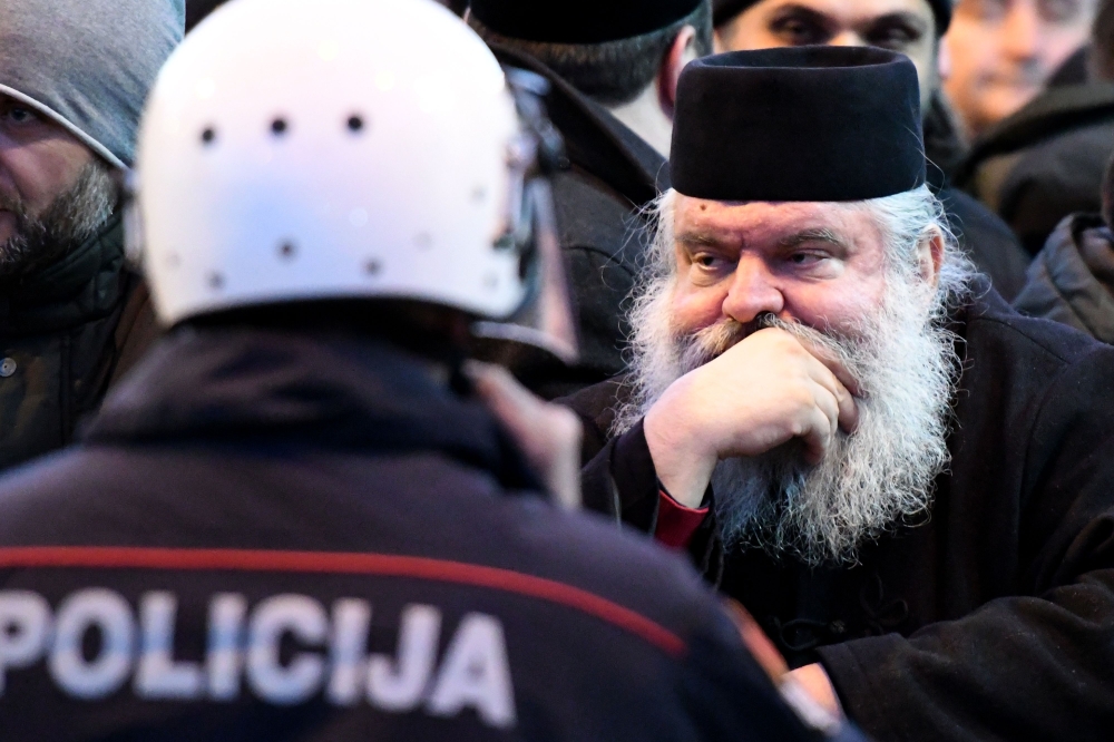 Serbian Orthodox Church clergy and believers stand in front of police near the parliament, ahead of the vote on a controversial law on religious freedom in Podgorica on December 26, 2019. AFP / Savo Prelevic
 