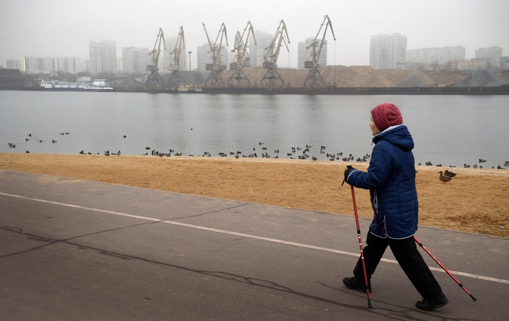A woman walks along the Channel of Moscow in Moscow on December 26, 2019. Winters in Moscow usually look like something out of a picture book: the Russian capital is covered in snow, people go skiing, and temperatures are well below freezing.   AFP / Alex