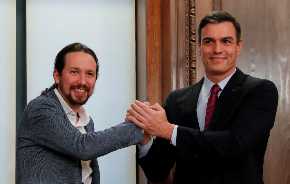 Spain's acting Prime Minister Pedro Sanchez and Unidas Podemos (Together We Can) leader Pablo Iglesias shake hands as they present their coalition agreement at Spain's Parliament in Madrid, Spain, December 30, 2019. Reuters/Susana Vera
