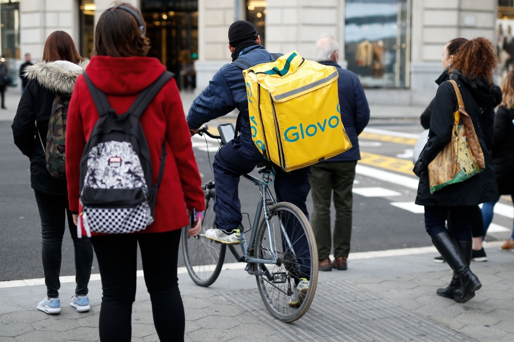 (FILES) In this file photo taken on December 03, 2019, a worker of Glovo, rides his bike during a delivery, on December 3, 2019 in Barcelona. AFP / PAU BARRENA