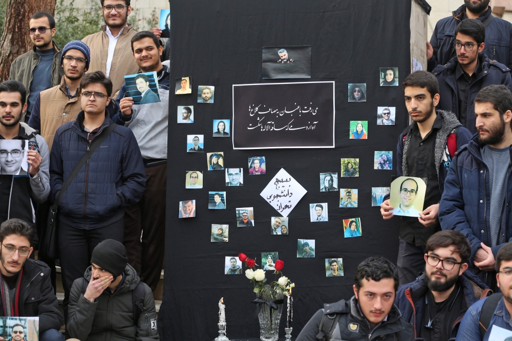 Iranian students hold pictures of victims during a memorial for the passengers of the Ukraine plane crash, in University of Tehran on January 14, 2020.   AFP / ATTA KENARE
