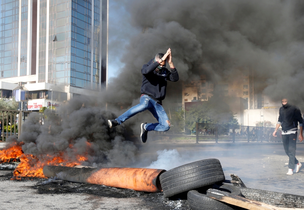 A protestor jumps over a burning barricade during a protest over economic hardship and lack of new government in Beirut, Lebanon January 14, 2020. Reuters/Mohamed Azakir
 